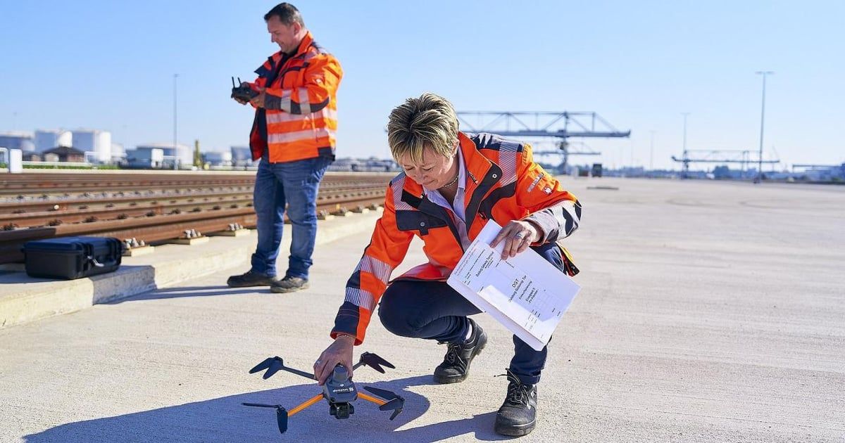 Zwei Personen in Warnkleidung bereiten auf einem Industriegelände eine Drohne vor
