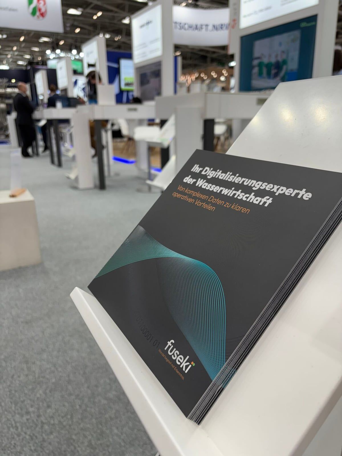 Broschüre „Ihr Digitalisierungsexperte der Wasserwirtschaft“ auf einem Messetisch