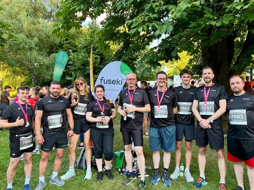 Laufteam mit Startnummern vor einer fuseki-Fahne beim Essener Firmenlauf